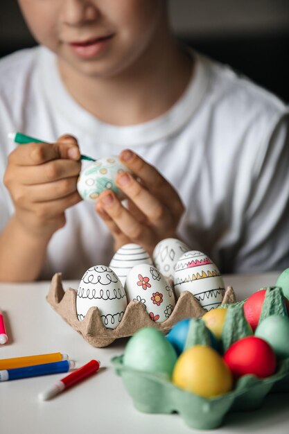Foto niño pinta huevos con diferentes colores.