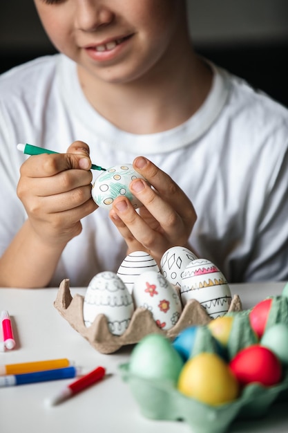 Niño pinta huevos con diferentes colores.