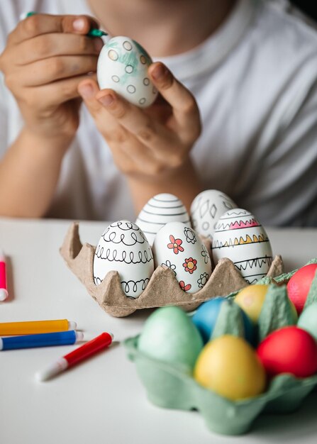 Foto niño pinta huevos con diferentes colores.