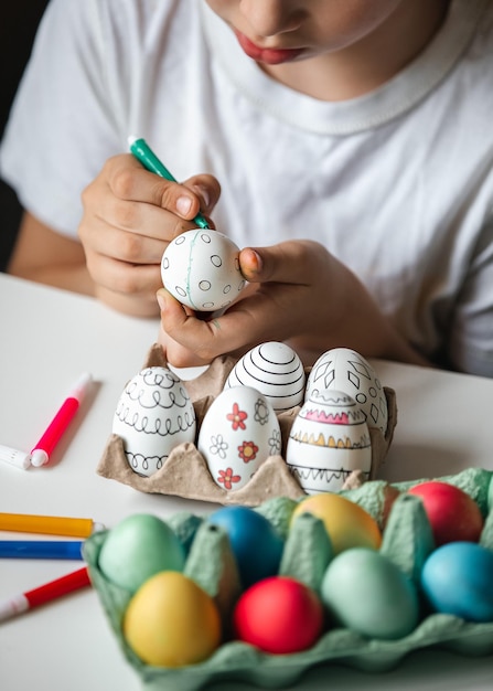 Foto niño pinta huevos con diferentes colores.