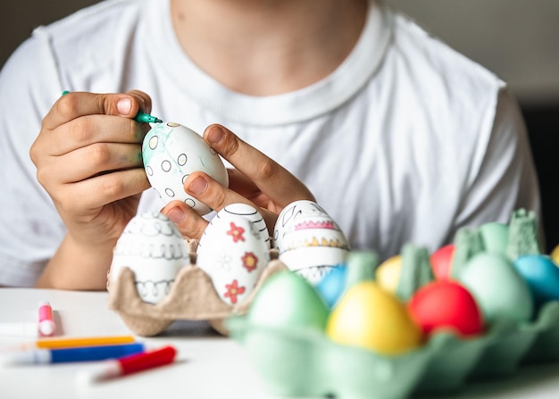 Foto niño pinta huevos con diferentes colores.