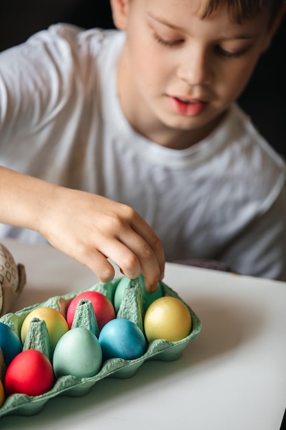 Niño pinta huevos con diferentes colores.