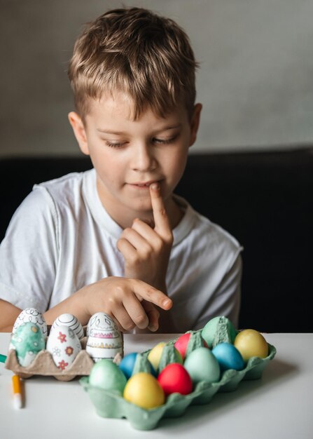 Foto niño pinta huevos con diferentes colores.