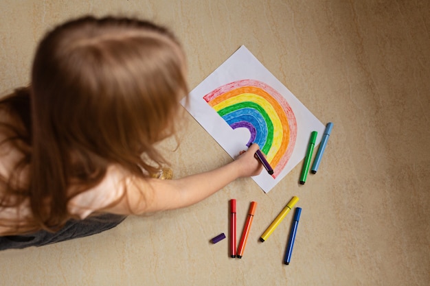 Niño pintando arcoíris durante la cuarentena de Covid-19 en casa