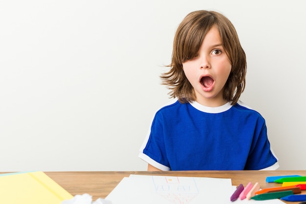 Niño pintando y haciendo los deberes en su escritorio se sorprendió.