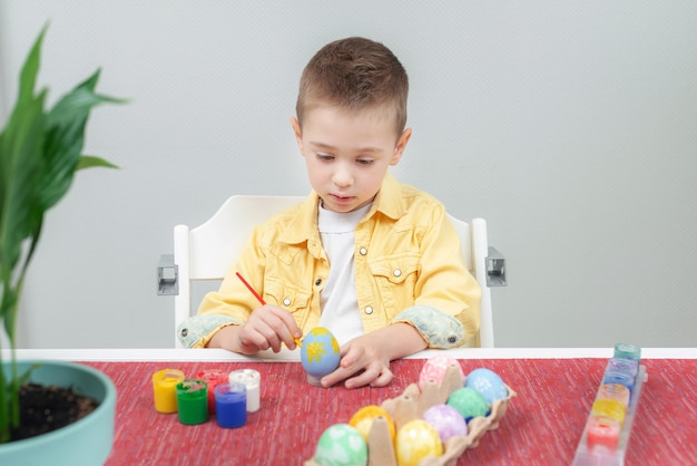 Niño pintando huevos de Pascua en casa