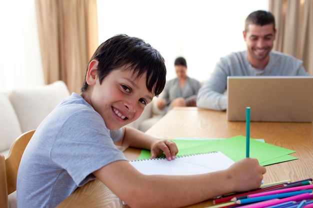 Niño pintando y padre usando una computadora portátil y lectura de la madre