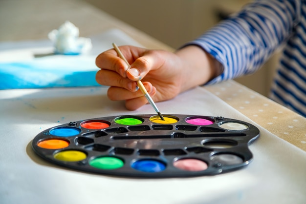 Niño pintando con pintura de acuarela en la escuela en casa.