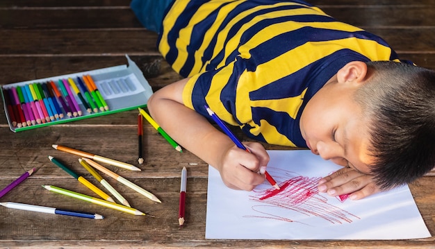 Foto niño pintando sobre papel blanco con color madera