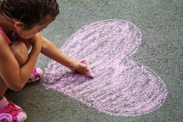 Niño pintó un corazón en el asfalto con tiza. enfoque selectivo arte.