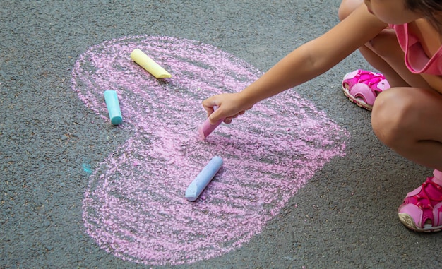 Niño pintó un corazón en el asfalto con tiza. enfoque selectivo arte.