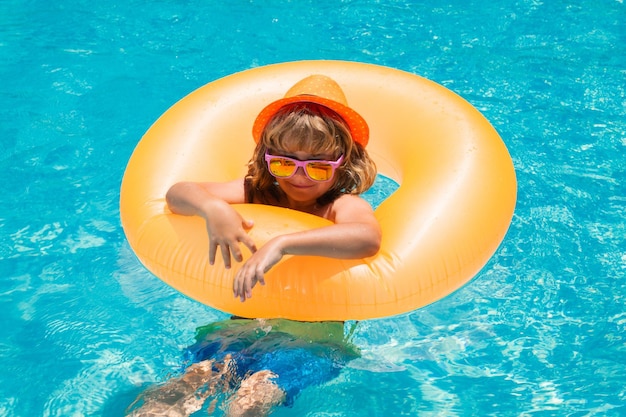 Niño en piscina en anillo inflable niño nadar con juguete de agua de flotador naranja deporte al aire libre saludable