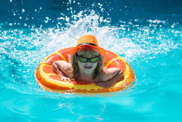 Niño en la piscina en el día de verano niños jugando en la piscina vacaciones para niños y concepto de vacaciones