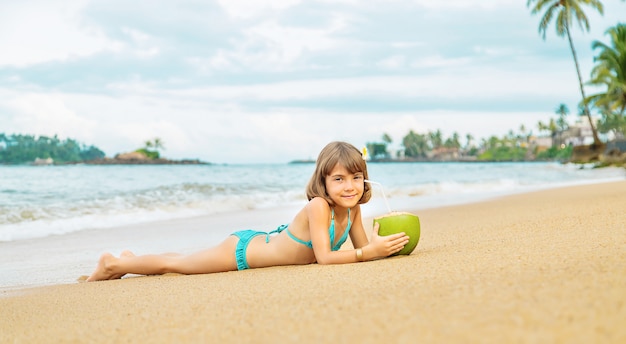 Un niño en la playa bebe coco.