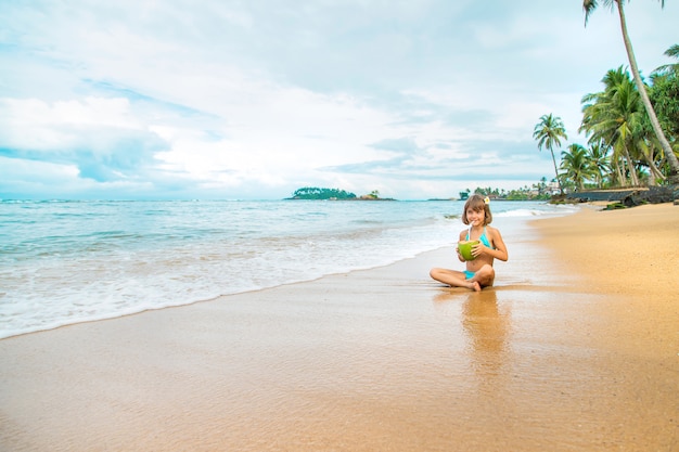 Un niño en la playa bebe coco.