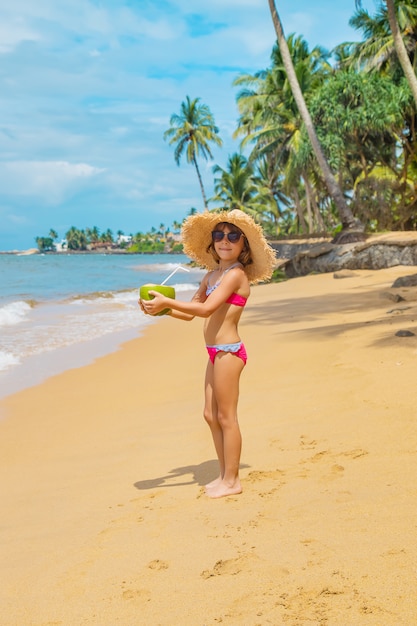 Un niño en la playa bebe coco.