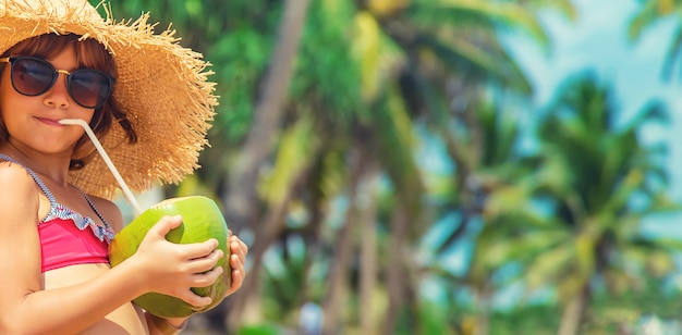 Un niño en la playa bebe coco