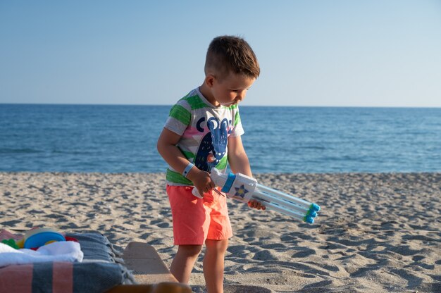 Niño en la playa con una pistola de agua.