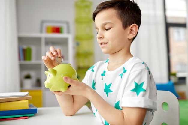 niño poniendo moneda en la alcancía en casa