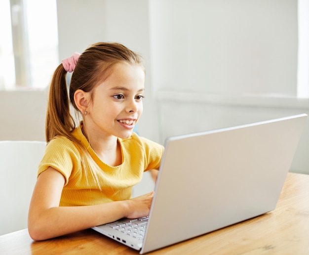 Niño portátil tecnología de computadora casa niña educación tarea niño aprendiendo internet infancia estudiante sentado conexión usando en línea