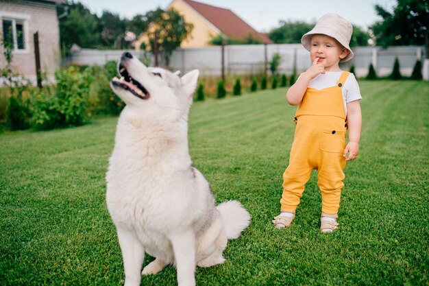 Un niño posando con el perro en el jardín.