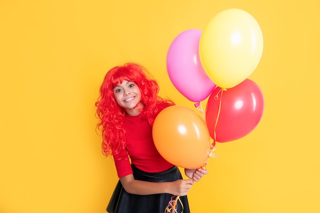 Niño positivo con globo de fiesta sobre fondo amarillo