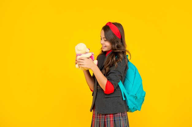 Niño positivo en uniforme sobre fondo amarillo. 1 de septiembre. infancia feliz. niño con juguete. adolescente lleva mochila. De vuelta a la escuela. día del conocimiento. concepto de educación.