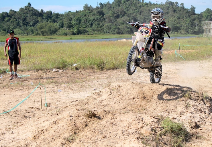 Foto un niño practicando motocross en el fondo supervisado por su padre watchful eyes