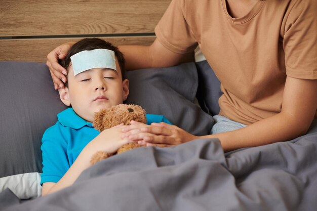 Niño preadolescente enfermo abrazando oso de peluche