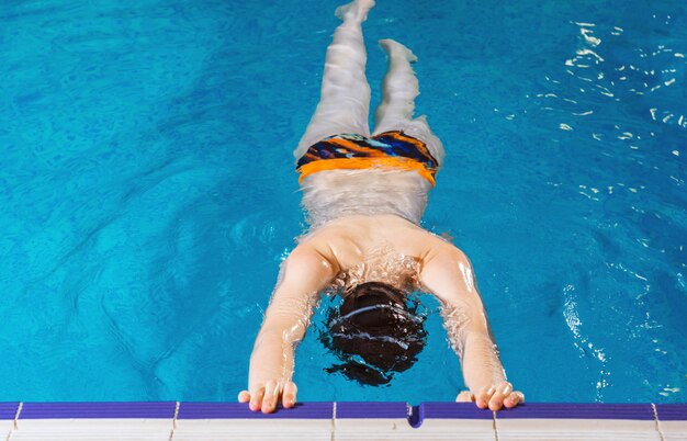 Niño preadolescente nadando y entrenando en la piscina