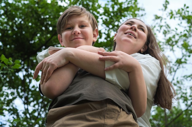 Niño preadolescente y su madre riendo y caminando en un jardín vibrante que muestra la alegría de la familia