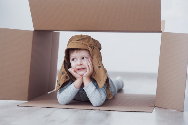 Niño preescolar niño jugando dentro de la caja de papel. Infancia, reparaciones y casa nueva.