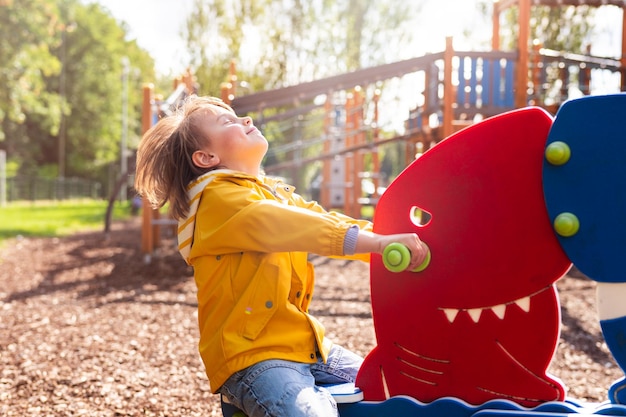 Niño preescolar en el patio de recreo para niños feliz niño emocional columpiándose en un tablero en un parque Concepto de infancia