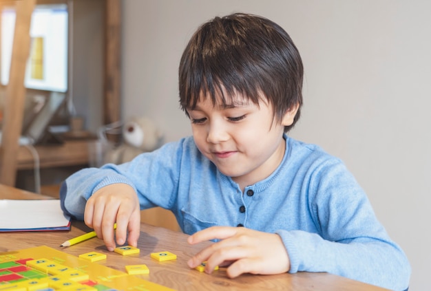 Foto niño preescolar que aprende el juego de palabras en inglés, niño niño concentrado con ortografía letra en inglés con los padres en casa educación a distancia, actividad para niños para la educación en el hogar durante el autoaislamiento