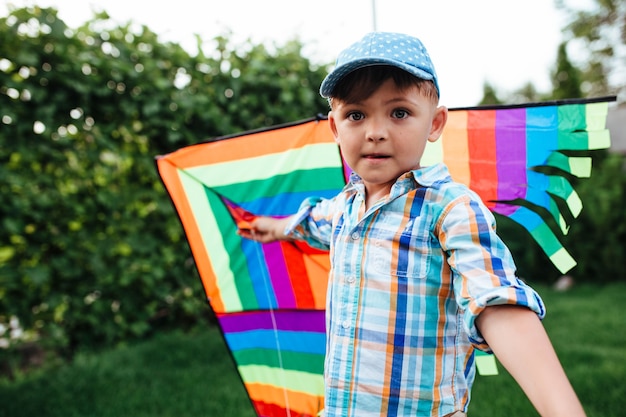 Niño preescolar volando una cometa voladora en el patio trasero