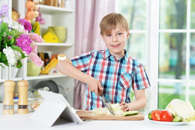 Niño preparando una deliciosa ensalada fresca en la cocina