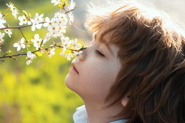 Niño de primavera de infancia feliz con árbol floreciente niño lindo en jardín de flores