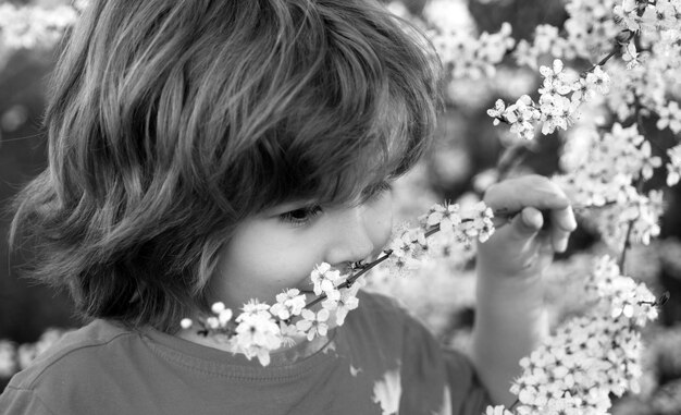 Niño de primavera en el parque floreciente árbol floreciente al aire libre del niño lindo en el jardín