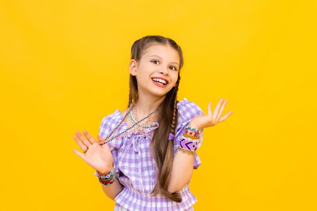 El niño se puso muchas pulseras hechas de cuentas y cuentas Una niña feliz está disfrutando de un adorno de cuentas Perlas para niños Fondo amarillo aislado
