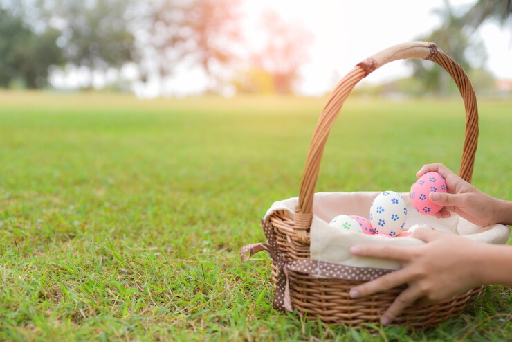 Un niño que se divierte con los huevos en el jardín en hierba verde.