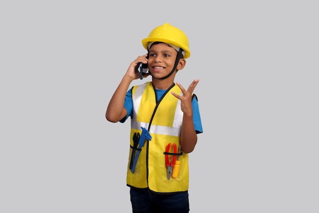 Foto un niño que llevaba un casco amarillo hablando por un teléfono celular.