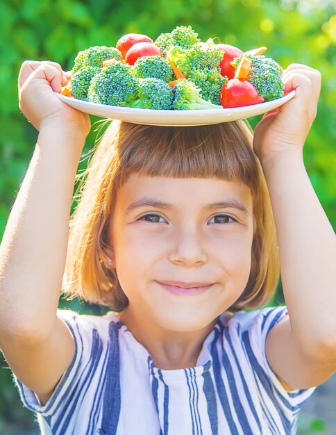 Niño que sostiene un plato con verduras