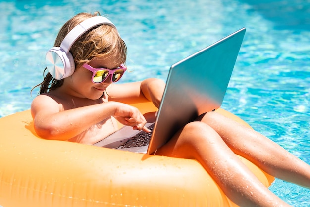 Niño que trabaja en la computadora portátil de la piscina viajes de verano de negocios