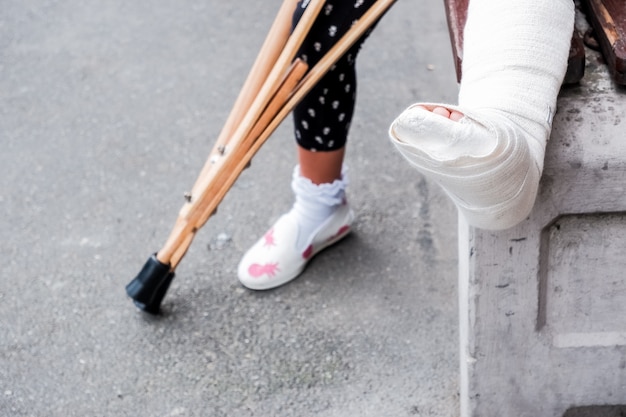 Niño que usa muletas y piernas rotas para caminar, pierna rota,