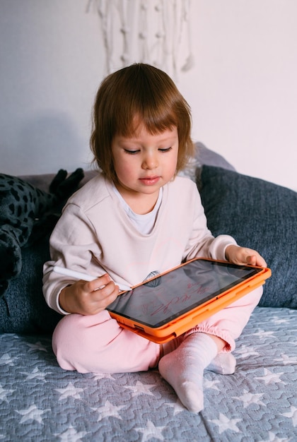 Niño que usa tecnología para niños pequeños en casa con una tableta y un lápiz óptico y dibuja