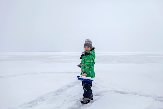 Niño quitando la nieve del hielo en el lago congelado, invierno, silencio y naturaleza salvaje, estilo de vida