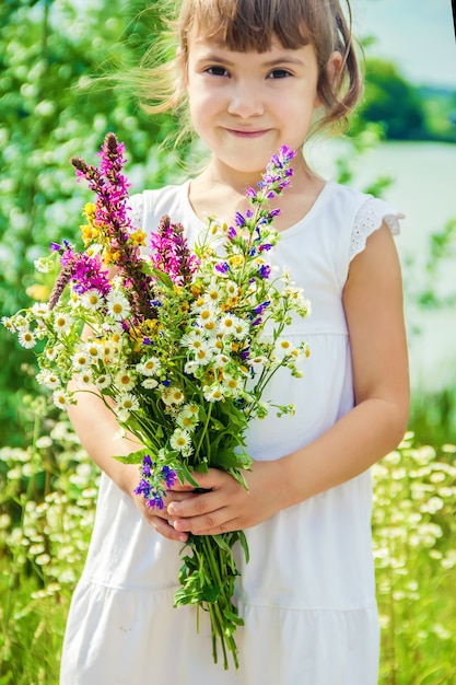 Niño con un ramo de flores silvestres. Enfoque selectivo naturaleza.