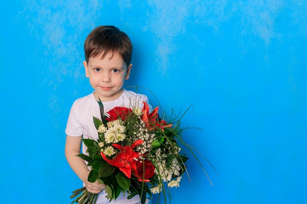 Un niño con un ramo sobre un fondo azul.