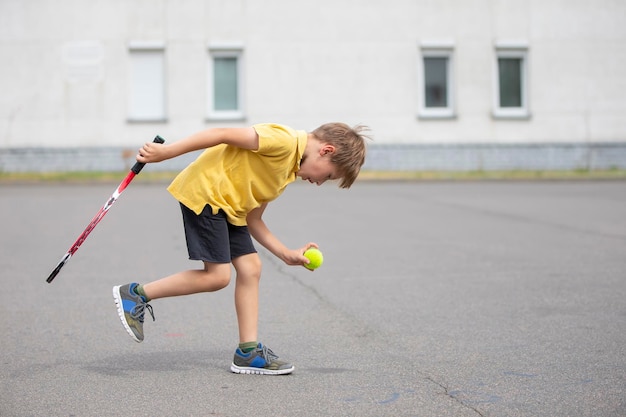 Niño con una raqueta de tenis y una pelota Niño tenista Colegial practica deportes