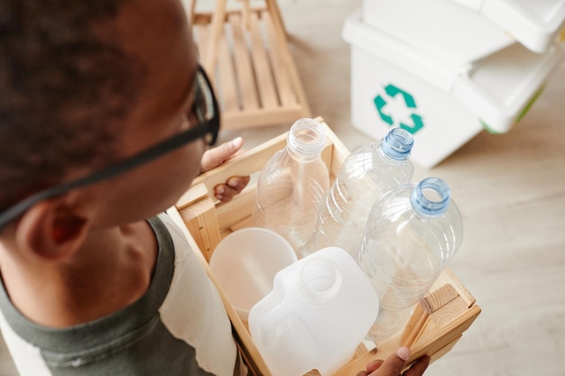 Foto niño reciclando botellas de plástico en casa